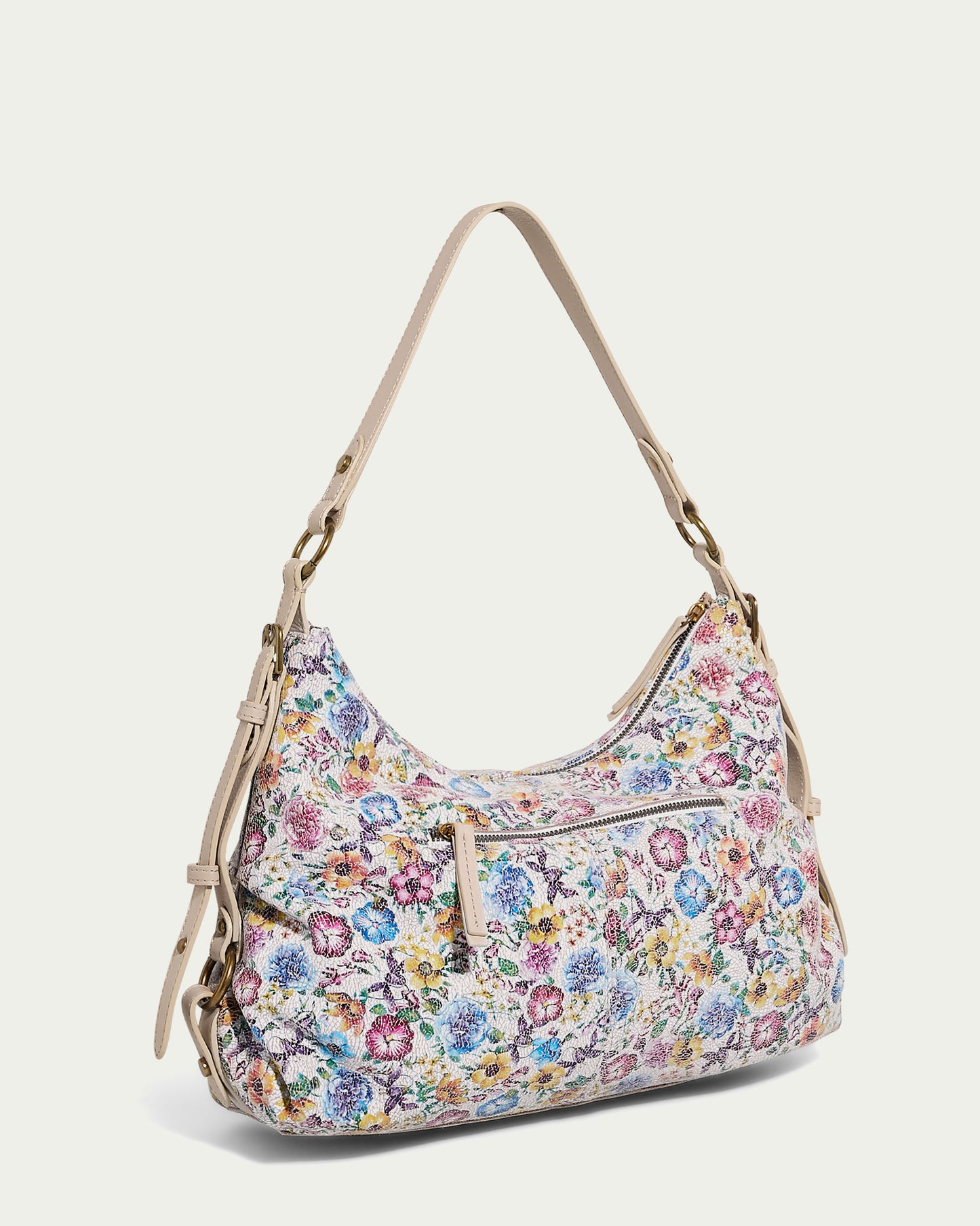 The Thayer Perfect Hobo from American Leather Co. is an ideal shoulder bag featuring a beige strap adorned with a vibrant floral pattern in shades of pink, blue, yellow, and green. Crafted from genuine leather, this stylish accessory includes a front zipper pocket and gold hardware accents. Adjustable straps and side buckles provide extra versatility.